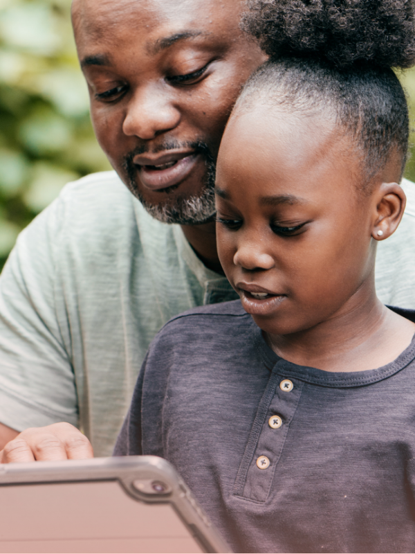 Father and daughter using a tablet together, an example of how to teach digital safety to kids at home.