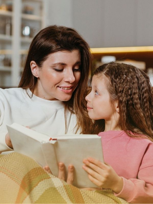 Mother and daughter sharing a book while cuddled on the couch