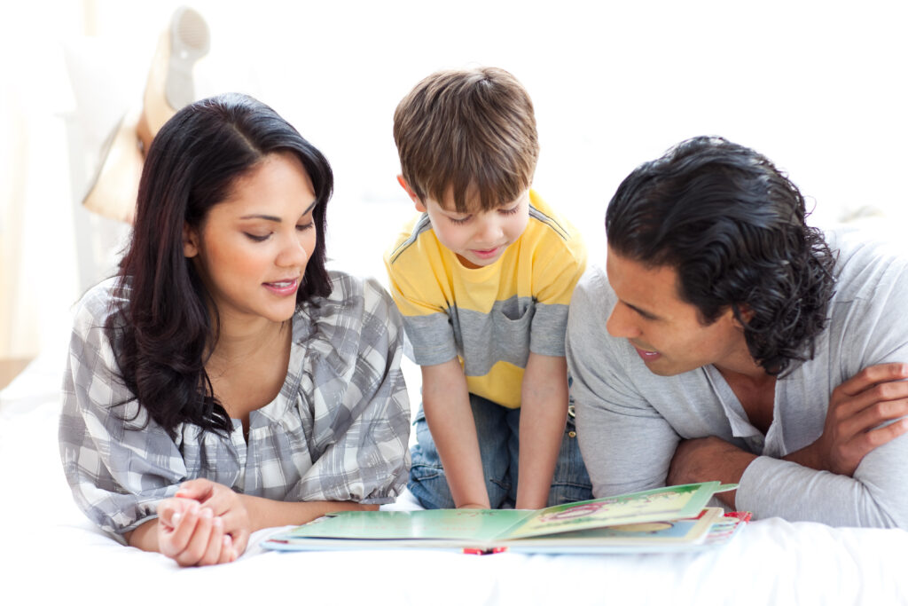 Parents and child reading a book together on the bed