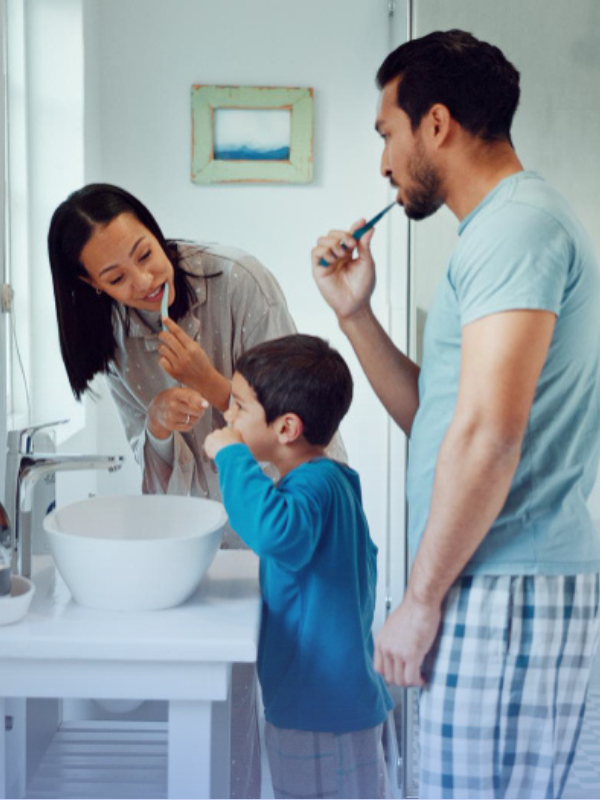 Parents and child brushing teeth together as part of healthy morning routines for working parents.
