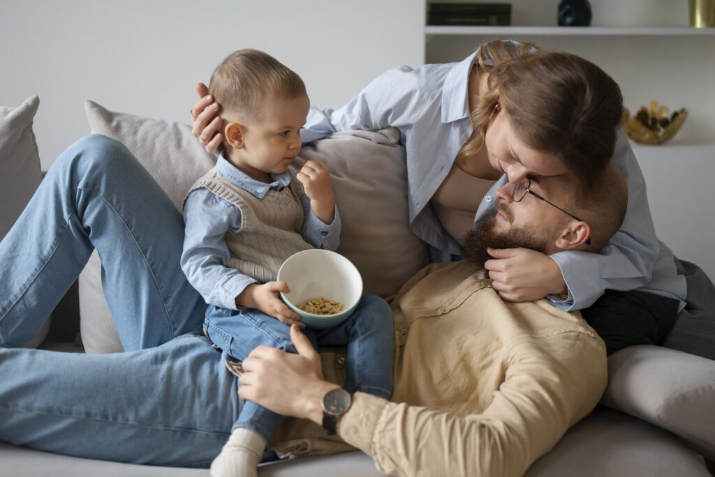 Parents relaxing on the couch with their toddler, sharing quality time as a form of stress relief for overwhelmed parents.